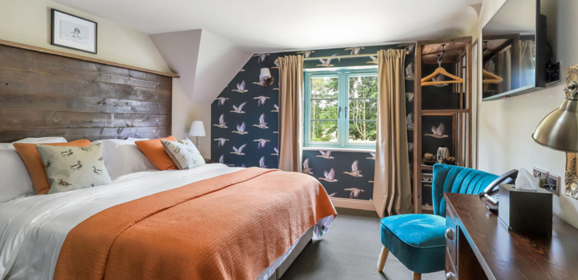 Hotel bedroom with kingsize bed, desk, TV and armchairs